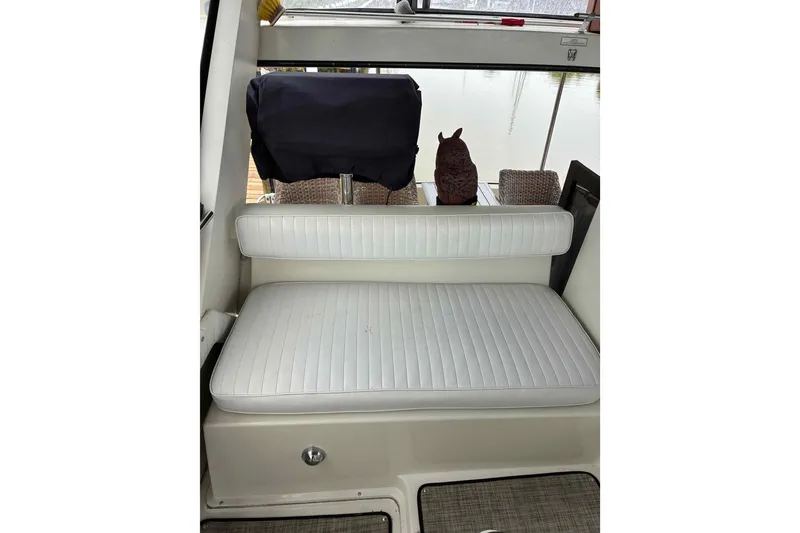 Slide: The Image of White cushioned seating on a 1989 Knight & Carver 3807 boat, with outdoor view. - 10