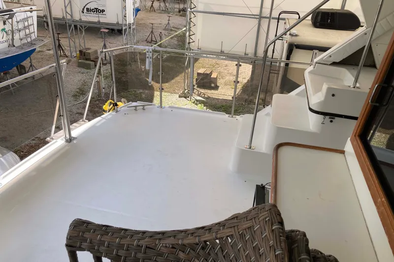 Slide: The Image of Deck view of 1989 Knight & Carver 3807 yacht, featuring wicker chair and stairs. - 14