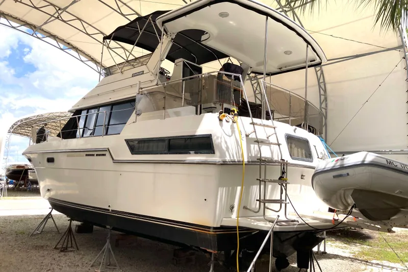 Slide: The Image of 1989 Knight & Carver 3807 yacht in dry dock, under a canopy, with inflatable boat attached. - 2