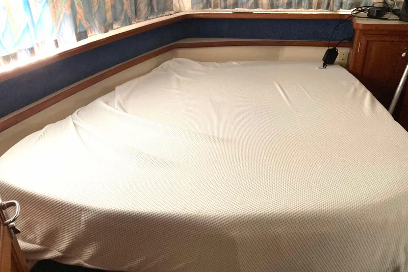 Slide: The Image of Cozy cabin bed in 1989 Knight & Carver 3807 yacht, featuring wooden cabinetry and patterned curtains. - 22