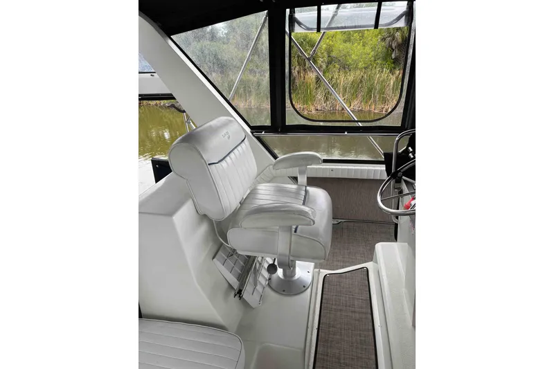Slide: The Image of Captain's chair on 1989 Knight & Carver 3807 yacht, overlooking serene waters and lush greenery. - 8