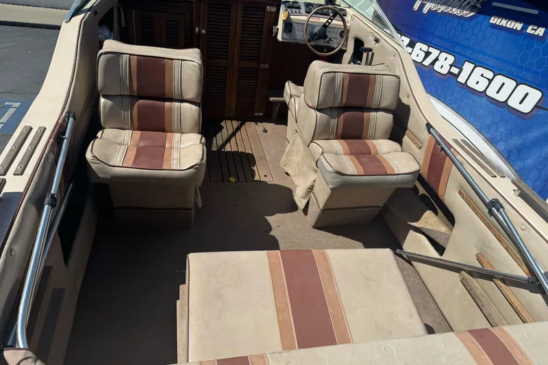 Slide: The Image of 1985 Invader 20 boat interior with beige and brown striped seats, steering wheel, and dashboard. - 10