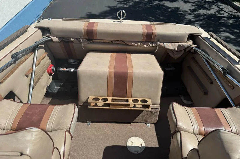 Slide: The Image of 1985 Invader 20 boat interior with beige and brown seating, cup holders, and storage compartments. - 11