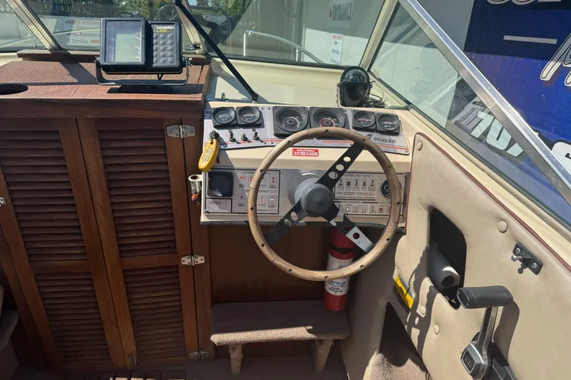 Slide: The Image of 1985 Invader 20 boat dashboard with steering wheel, gauges, and navigation equipment. - 15