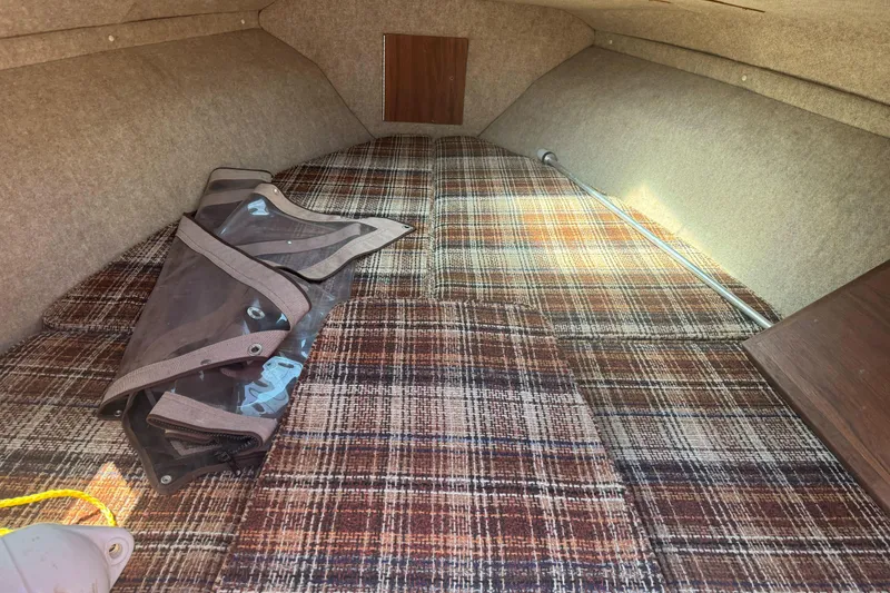 Slide: The Image of Interior cabin of 1985 Invader 20 boat with plaid upholstery and storage compartment. - 20