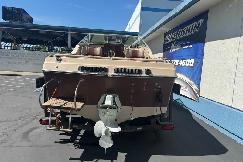 Slide: The Image of 1985 Invader 20 boat parked outside a building, rear view with propeller visible. - 9