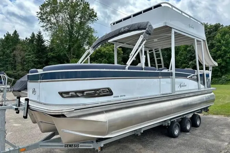 The Image of 2023 Avalon Catalina 2585 CRFS Funship pontoon boat on trailer, surrounded by trees. - 1