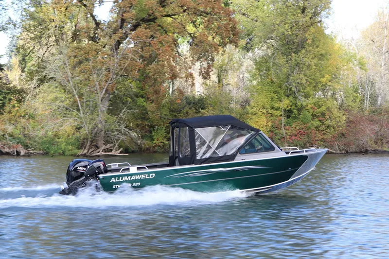 The Image of 2026 Alumaweld Stryker 220 boat cruising on a scenic river with lush greenery. - 0
