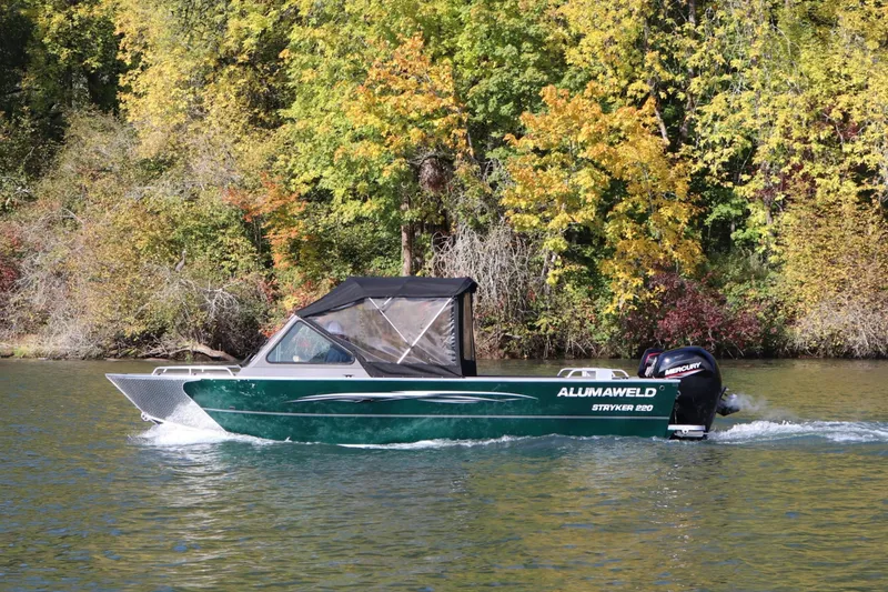 Slide: The Image of 2026 Alumaweld Stryker 220 boat cruising on a scenic lake with autumn foliage. - 2