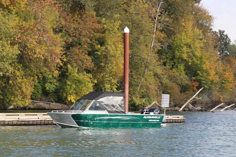 Slide: The Image of 2026 Alumaweld Stryker 220 boat cruising on a scenic lake with autumn foliage. - 40