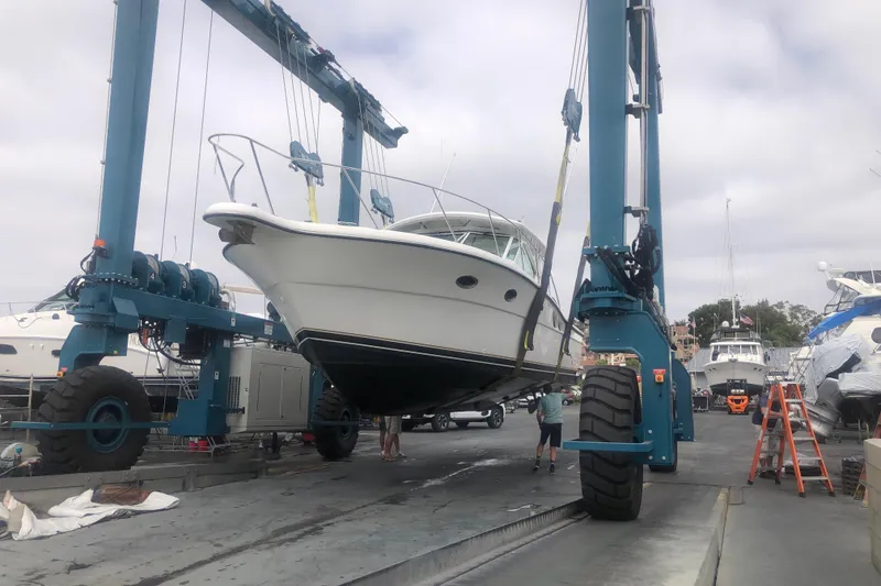 Slide: The Image of 2001 Tiara Yachts 3500 Open being lifted by a boat hoist at a marina. - 3