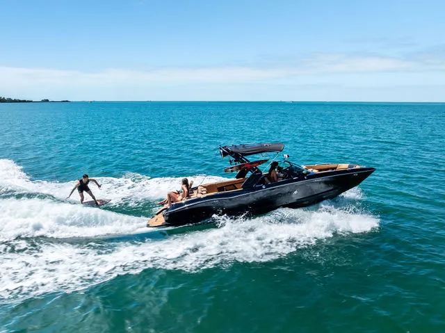 Slide: The Image of 2024 MasterCraft X24 boat on a serene lake with lush trees in the background. - 3