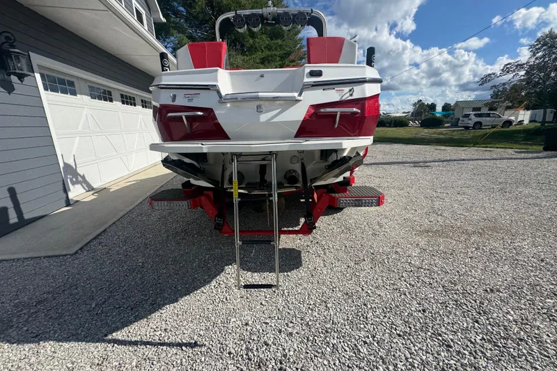 Slide: The Image of 2020 MasterCraft XStar boat rear view with ladder, parked on gravel driveway. - 14