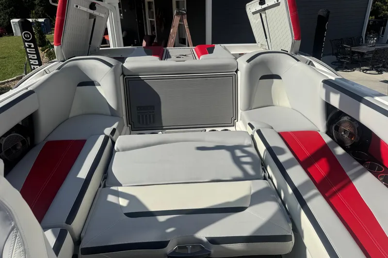Slide: The Image of 2020 MasterCraft XStar boat interior with red and gray seating, open storage compartments. - 21
