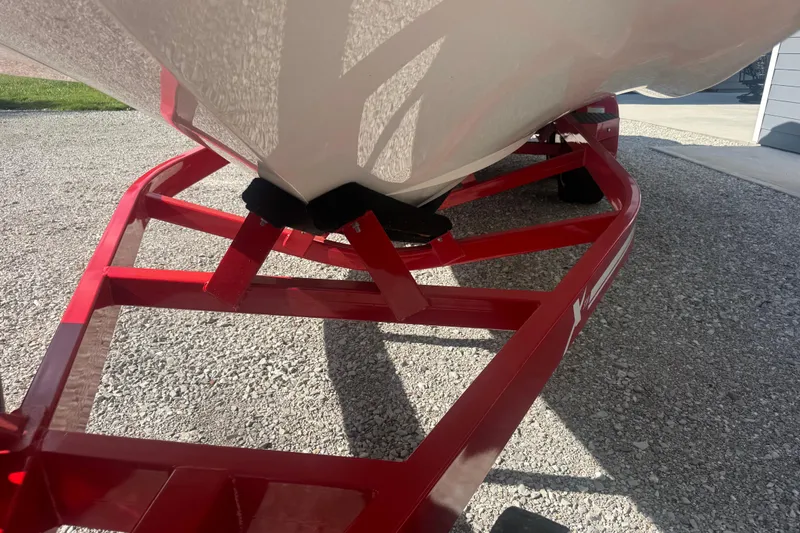 Slide: The Image of 2020 MasterCraft XStar boat on a red trailer, parked on gravel. - 24