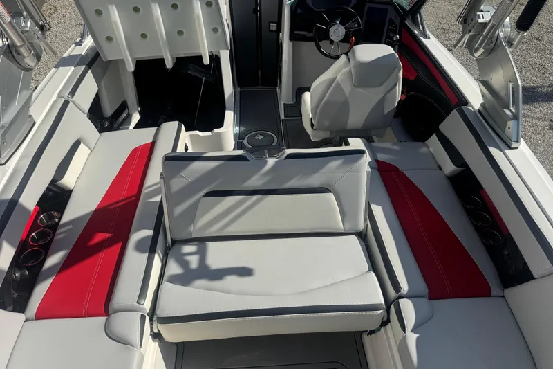 Slide: The Image of 2020 MasterCraft XStar boat interior with red and gray seating, steering wheel, and cup holders. - 34