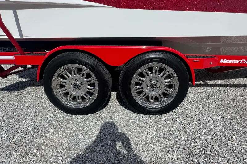 Slide: The Image of 2020 MasterCraft XStar trailer with dual chrome wheels on gravel surface. - 36