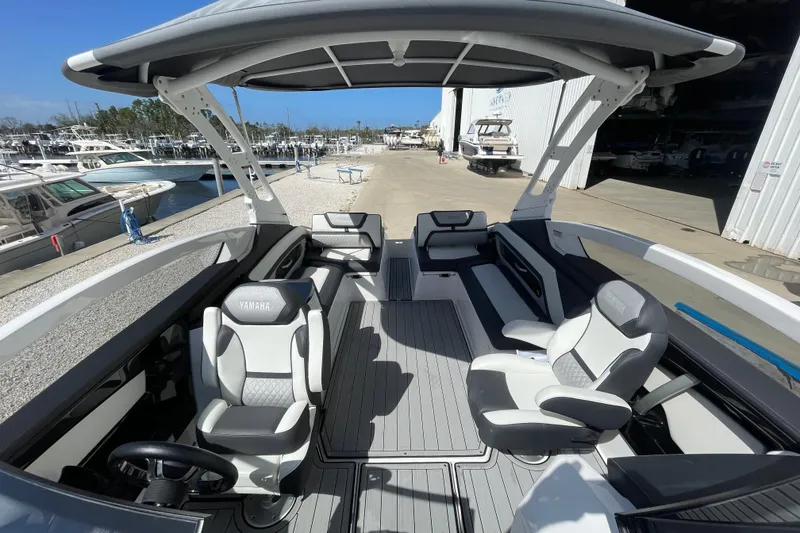 Slide: The Image of 2021 Yamaha Boats 275SE interior with sleek seating and modern design at a marina. - 11