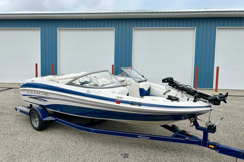 Slide: The Image of 2004 Tahoe Q4 boat on trailer, parked in front of blue garage doors. - 2
