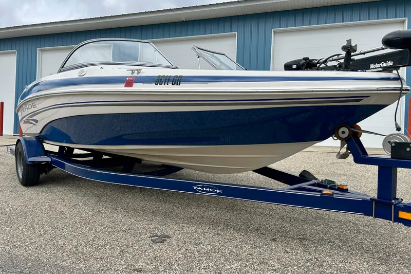 Slide: The Image of 2004 Tahoe Q4 boat on trailer, parked outside blue garage doors. - 4