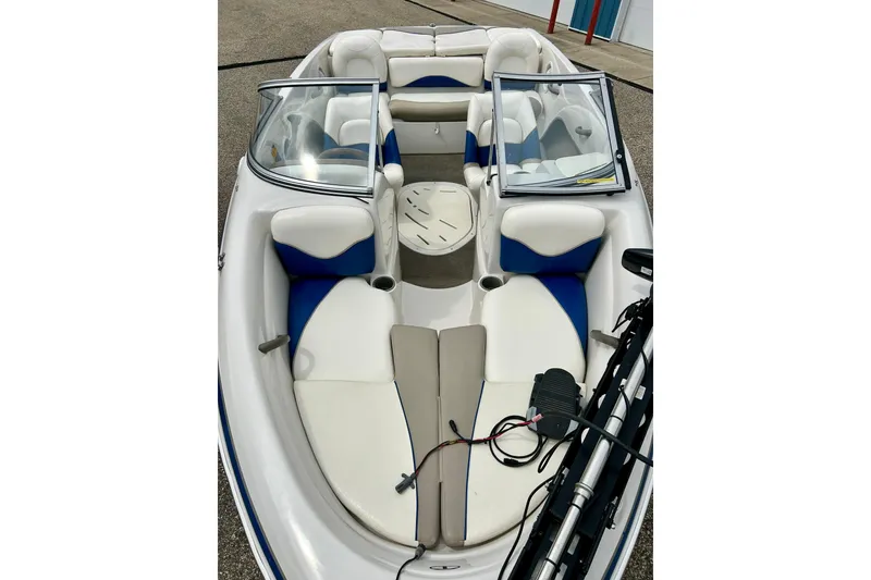 Slide: The Image of 2004 Tahoe Q4 boat interior with white and blue seating, open windshield, and storage compartments. - 6