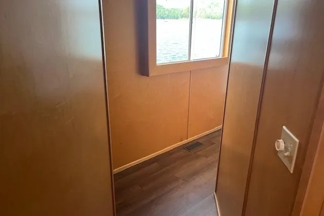 Slide: The Image of Interior view of a 2003 Fantasy 18x80 Houseboat with wood paneling and window. - 12