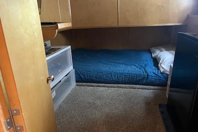 Slide: The Image of Small bedroom in a 2003 Fantasy 18x80 Houseboat with blue bedding and storage drawers. - 21