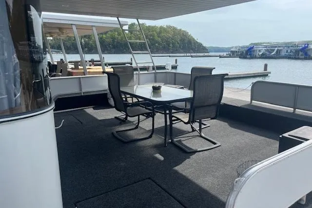 Slide: The Image of 2003 Fantasy 18x80 Houseboat with outdoor seating on a serene lake. - 4