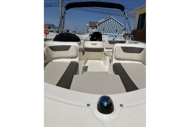Slide: The Image of 2019 Bayliner Element E16 boat interior with seating and canopy, parked near houses. - 3