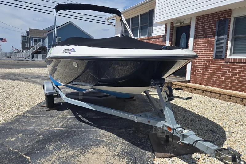 Slide: The Image of 2019 Bayliner Element E16 boat on trailer, parked beside a brick house. - 7