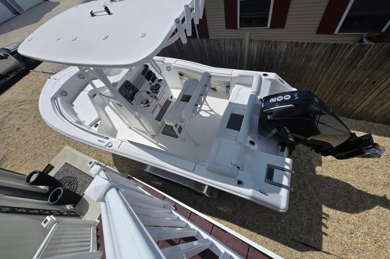 Slide: The Image of 2013 Tidewater 210 LXF boat with outboard motor, parked on gravel near a wooden fence. - 4