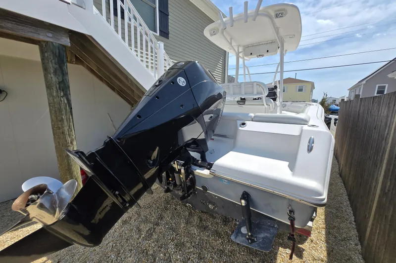 Slide: The Image of 2013 Tidewater 210 LXF boat with outboard motor, parked beside a house. - 5