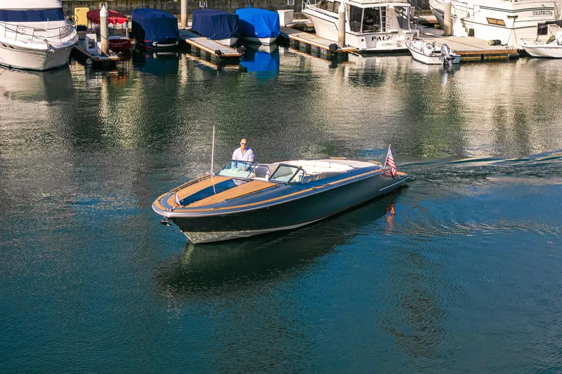 Slide: The Image of 2021 Chris-Craft Corsair 34 cruising in a marina, surrounded by docked boats. - 2