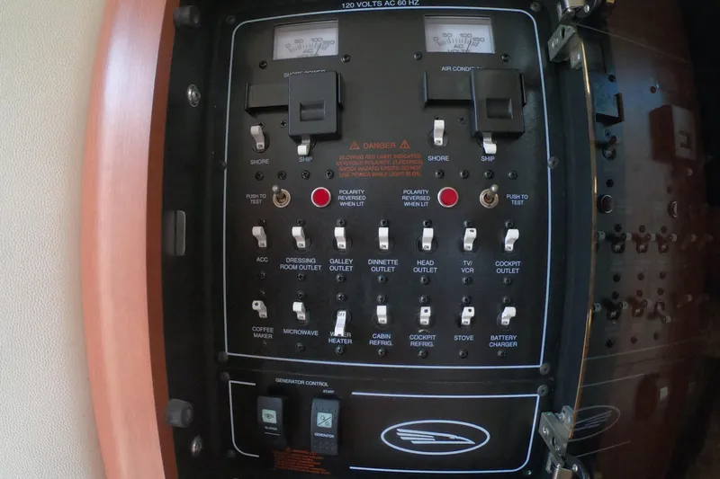 Slide: The Image of AC/DC Power Control panel of a 2003 Chaparral 320 Signature boat with various switches and indicators. - 23