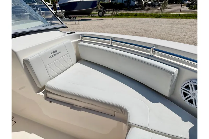 Slide: The Image of 2023 Cobia 220 Dual Console boat interior with white seating and speaker. - 11