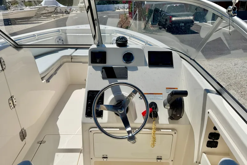 Slide: The Image of 2023 Cobia 220 Dual Console boat cockpit with steering wheel and control panel. - 13