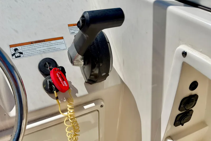 Slide: The Image of 2023 Cobia 220 Dual Console boat controls with safety lanyard and warning label. - 18