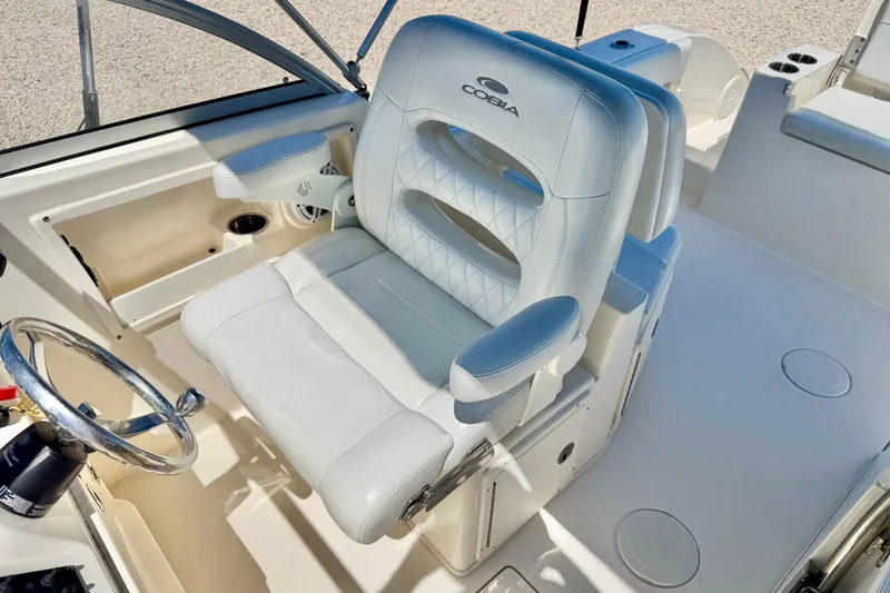 Slide: The Image of 2023 Cobia 220 Dual Console boat interior with plush captain's seat and steering wheel. - 19