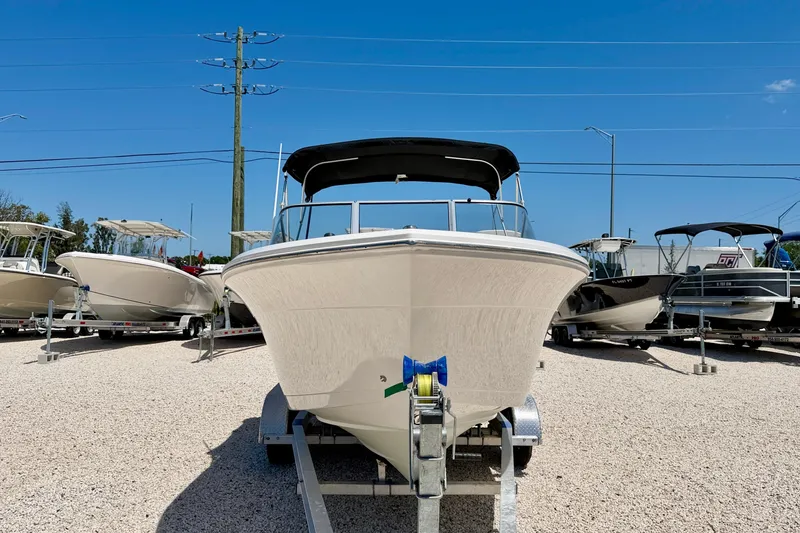 Slide: The Image of 2023 Cobia 220 Dual Console boat on trailer in sunny outdoor showroom. - 2