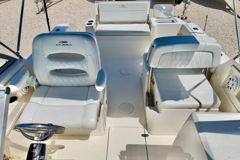 Slide: The Image of 2023 Cobia 220 Dual Console boat interior with white seating and steering wheel. - 20