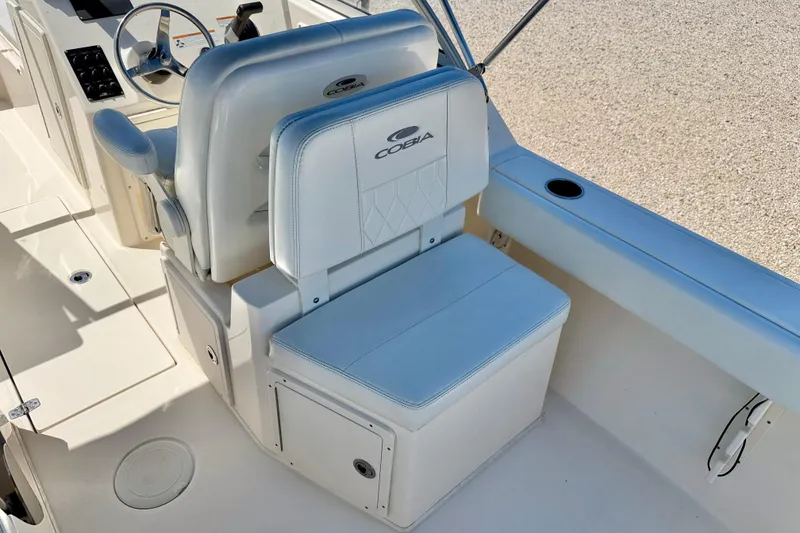 Slide: The Image of 2023 Cobia 220 Dual Console boat interior with white seating and steering wheel. - 22