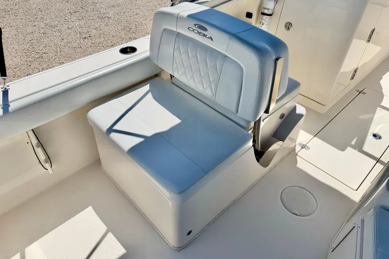 Slide: The Image of 2023 Cobia 220 Dual Console boat seat with white upholstery and storage compartment. - 23
