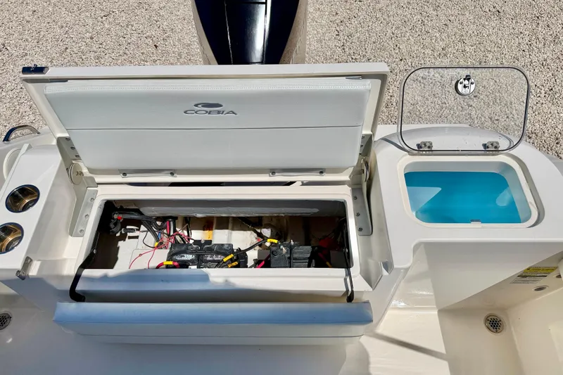 Slide: The Image of 2023 Cobia 220 Dual Console boat battery compartment and storage area. - 27