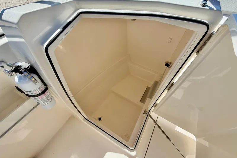 Slide: The Image of 2023 Cobia 220 Dual Console storage compartment with fire extinguisher, open hatch view. - 29