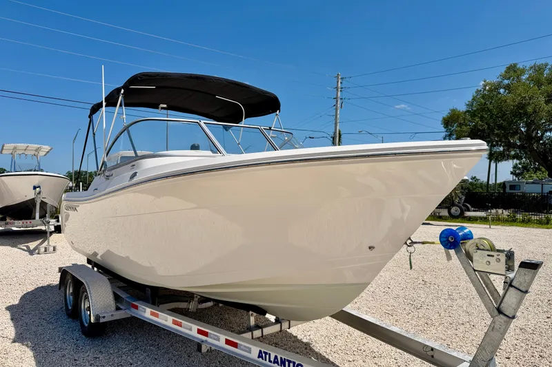 Slide: The Image of 2023 Cobia 220 Dual Console boat on trailer under clear blue sky. - 3