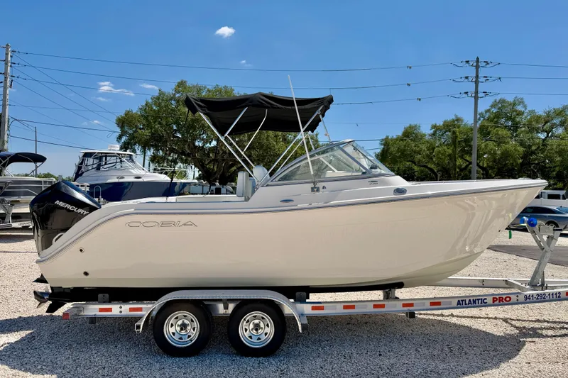 Slide: The Image of 2023 Cobia 220 Dual Console boat on trailer under clear blue sky. - 4