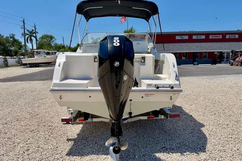 Slide: The Image of 2023 Cobia 220 Dual Console boat with outboard motor, parked on gravel lot. - 6