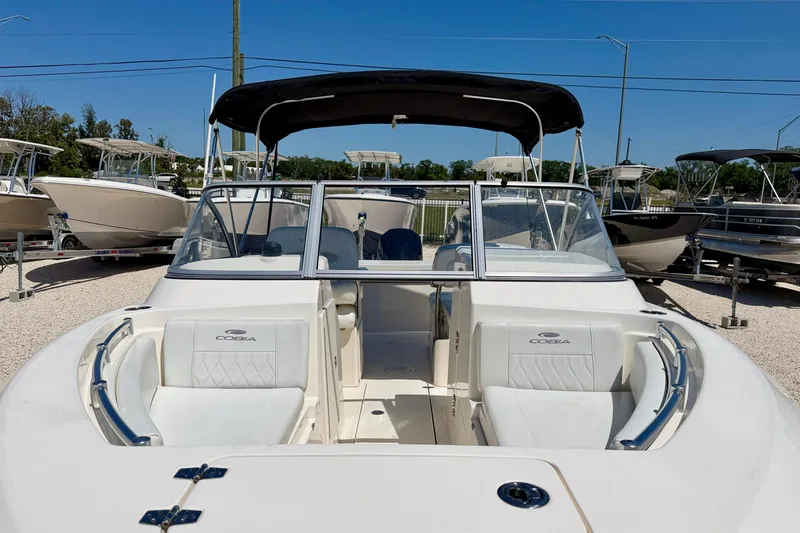 Slide: The Image of 2023 Cobia 220 Dual Console boat with white seating and black canopy. - 8