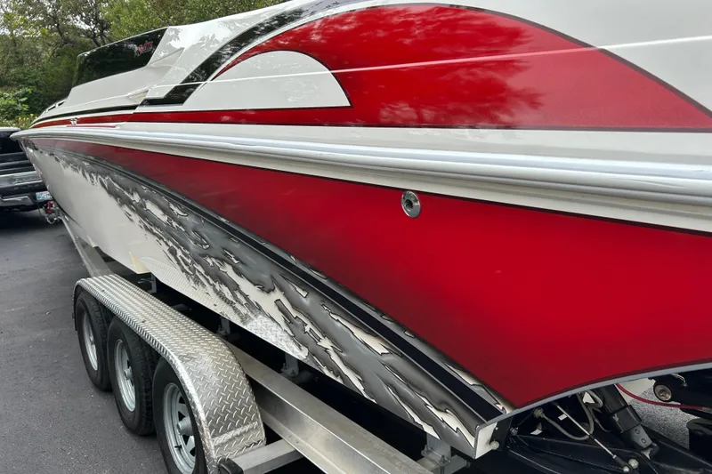 Slide: The Image of 2002 Fountain 38 Lightning boat with red and white design on a trailer. - 20