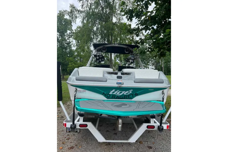 Slide: The Image of 2022 Tigé Z1 boat with "No Ragrets" decal, parked on a trailer, surrounded by trees. - 5